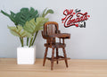 1:12 scale miniature wood high chair with tray in dark brown with spindle back, shown beside a potted plant