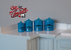 1:12 scale miniature kitchen canister set with lids in blue with labels, set of 4 graduated sizes, on a white counter