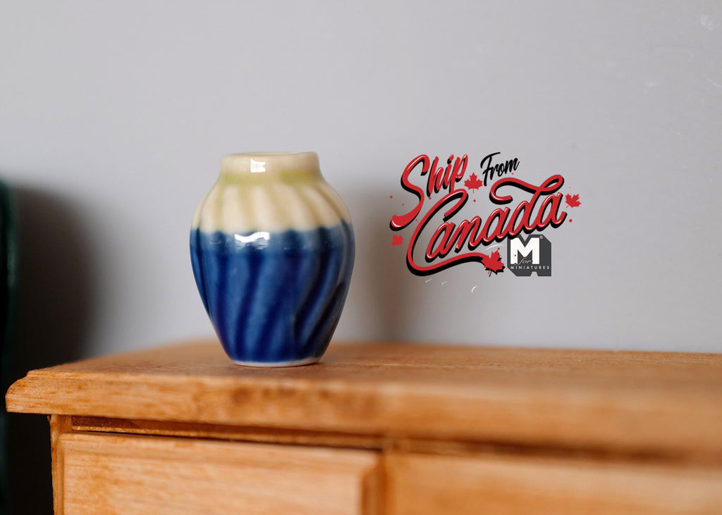 1:12 scale miniature ceramic plum vase in two tone blue and cream with a ribbed body, on a wood dresser