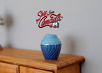 1:12 scale miniature ribbed ceramic plum vase in blue with a light to dark glaze, shown on a wood dresser