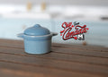 1:12 scale miniature light blue ceramic cooking pot with lid and 2 side handles, shown on a dark wood counter