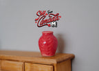 1:12 scale miniature red ceramic plum vase, round with a short neck and glossy glaze, shown on a wood cabinet