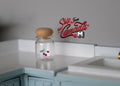 1:12 scale miniature glass jar with small red fruit design and cork lid, shown on a mint kitchen counter