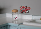 1:12 scale miniature glass jar with small red fruit design and cork lid, shown on a mint kitchen counter
