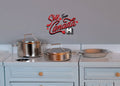 1:12 scale miniature silver metal pot and pan cooking set with lids, shown on a white kitchen stove