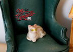 1:12 scale miniature resin lying kitten, ginger tabby in cream and orange with yellow eyes, shown on a green armchair