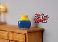 1:12 scale miniature ceramic plum vase with yellow and blue glaze, shown on a wood dresser