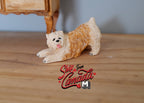 1:12 scale miniature resin Soft Coated Wheaten Terrier dog lying in a play bow pose, cream and tan, on a wood floor