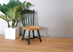 1:12 scale miniature wood spindle back chair in dark green with natural wood seat, shown beside a potted plant