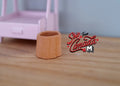 1:12 scale miniature clay faux log planter in tan with a bark texture, shown on a wood table