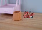 1:12 scale miniature clay faux log planter in tan with a bark texture, shown on a wood table