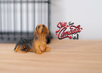 1:12 scale miniature lying Yorkshire terrier dog figure in black and tan, shown on a wood floor by a pet crate