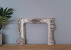 1:12 scale miniature resin Victorian style fireplace mantel in aged gray with ornate relief, shown with a coin for scale