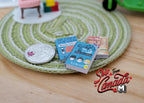 1:12 scale miniature children's picture books that can open, set of 3, shown on a green woven rug beside a coin