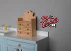 1:12 scale miniature unpainted wood hanging spice shelf with 3 drawers and shaped back, shown on a blue cabinet