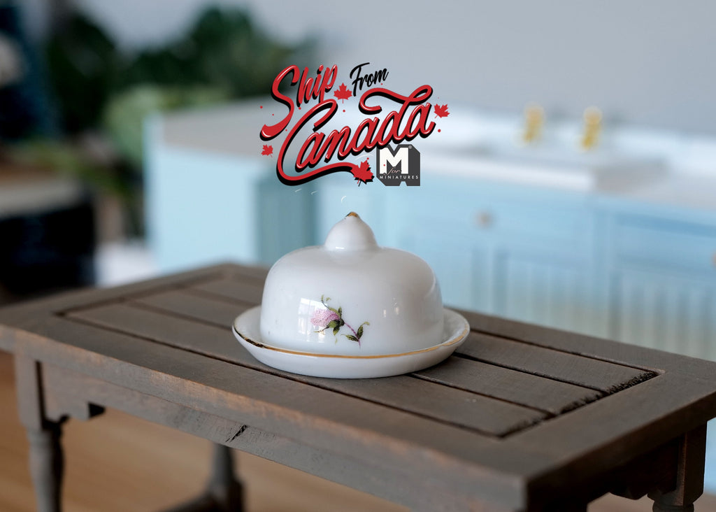 1:12 scale miniature ceramic serving plate with cover dome, 2 pieces, white with pink floral accent, on a dark wood table