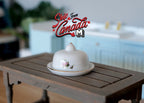 1:12 scale miniature ceramic serving plate with cover dome, 2 pieces, white with pink floral accent, on a dark wood table