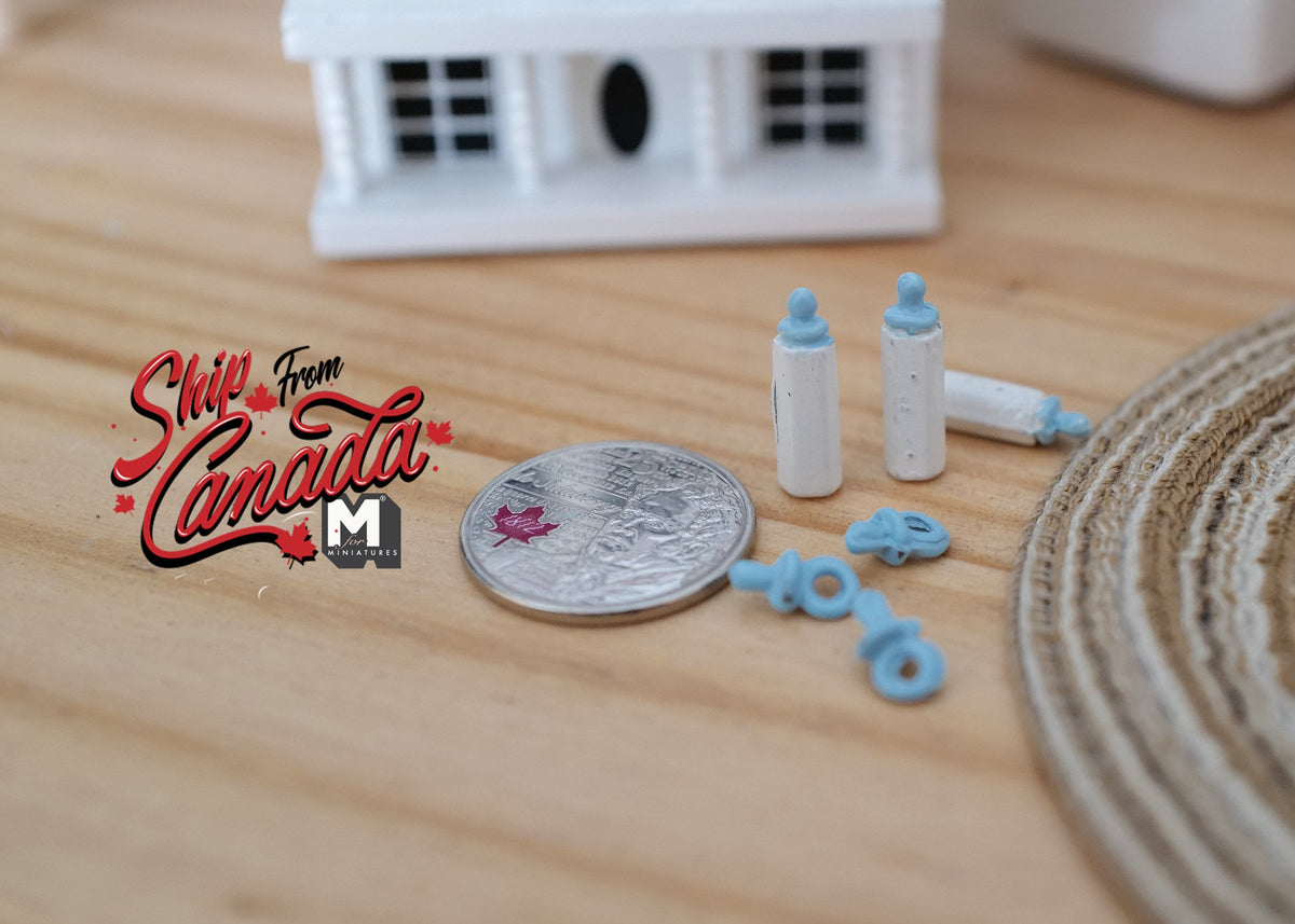 1:12 scale miniature baby feeding set in blue with bottles and pacifiers, shown beside a coin for scale