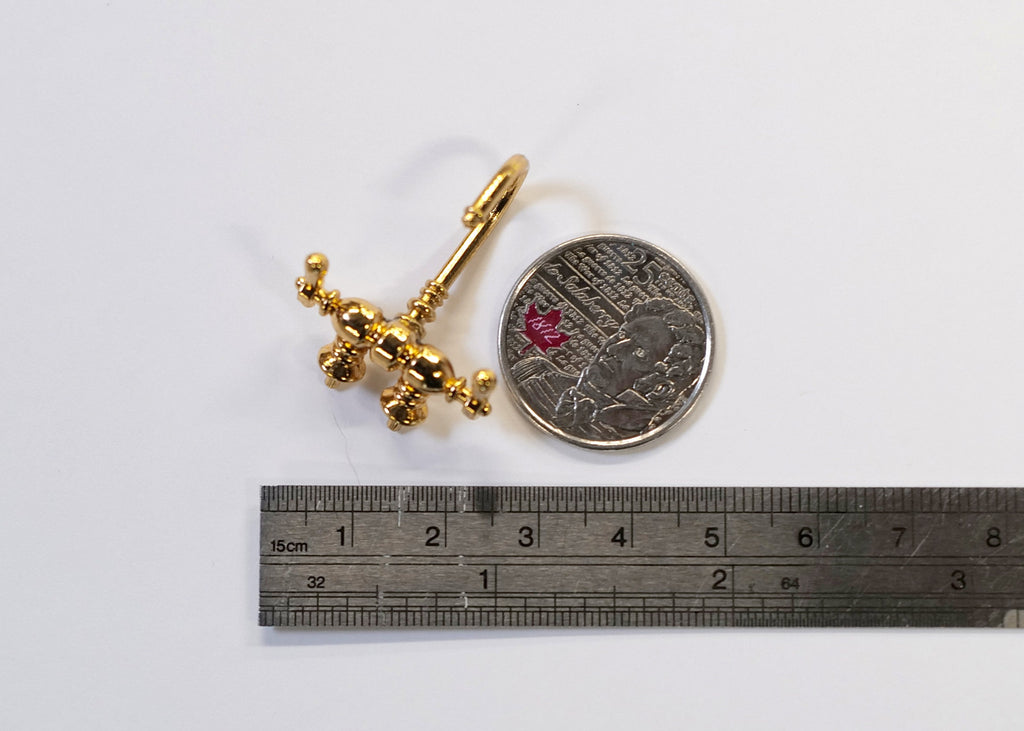 1:12 scale miniature double handle faucet in gold with curved spout, shown with a coin and a ruler for scale