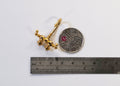 1:12 scale miniature double handle faucet in gold with curved spout, shown with a coin and a ruler for scale