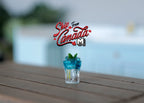 1:12 scale miniature lime soda with ice and mint leaves in a clear tumbler glass, shown on a wood plank table