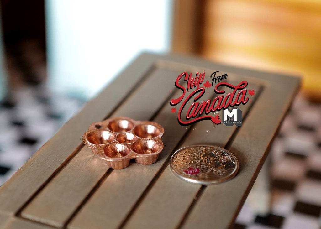 1:12 scale miniature metal popover pan in copper with 6 cups, on a gray wood table beside a coin for scale