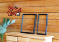 1:12 scale miniature black metal picture frames, set of 2, thin rectangular frames, shown on a wood dresser