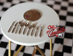 1:12 scale miniature metal flatware set in silver, knives, forks and spoons, set of 9, on a white table with a coin