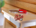 1:8 scale miniature red stapler with silver base, shown on a wood desk beside a coin for scale