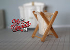 1:12 scale miniature foldable laundry basket with crossed wood frame and white fabric bag, on a gray tiled floor