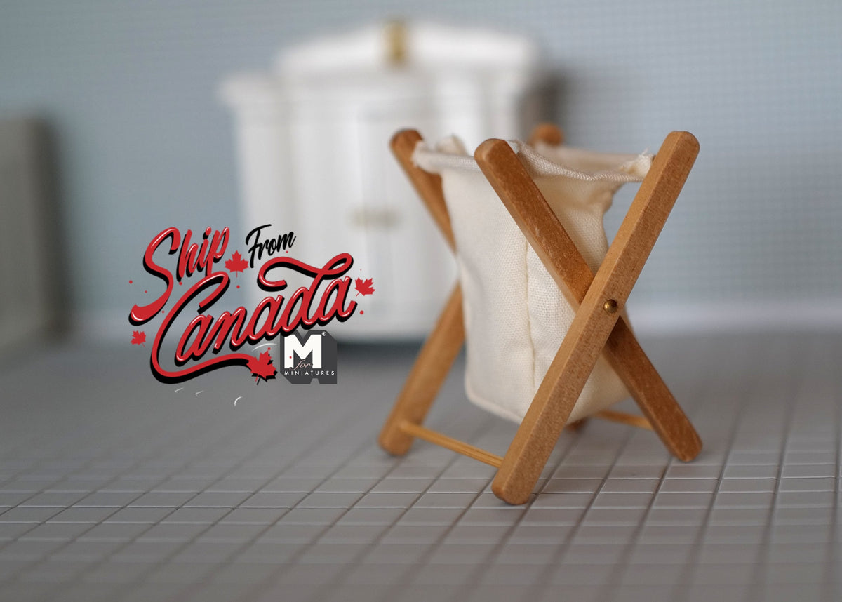 1:12 scale miniature foldable laundry basket with crossed wood frame and white fabric bag, on a gray tiled floor