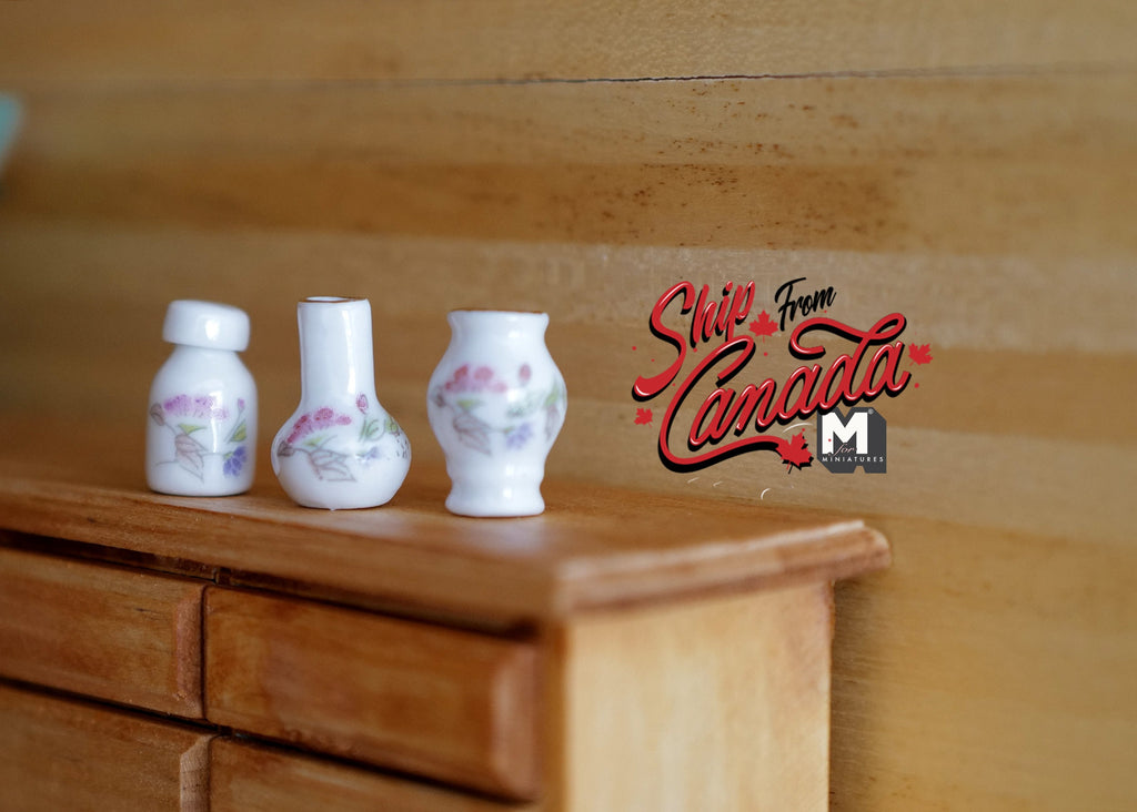 1:12 scale miniature ceramic vase set of 3 in pear, plum and rouleau shapes, white with blue floral, on a wood dresser