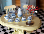 1:12 scale miniature porcelain tea set with blue and white leaf pattern, 15 pieces, shown on a cream oval table beside a coin