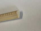 Miniature beaded edge wood trim molding for walls, unfinished, close up of the beaded profile