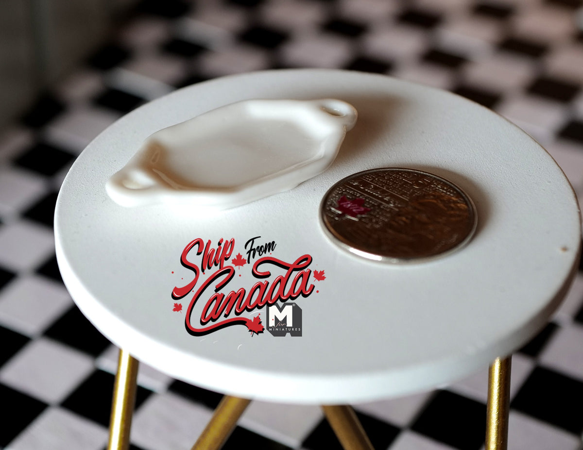 1:12 scale miniature ceramic oval tray in white with side handles, on a round table beside a coin for scale