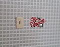 1:12 scale miniature modern rocker wall switch in beige, shown mounted on a white square tile wall