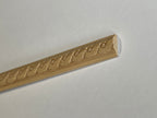 Miniature carved scroll wood trim molding for walls, long natural wood strip with a wave pattern, shown close up