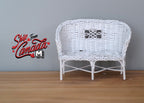 1:12 scale miniature white metal wicker style garden loveseat with a woven curved back, shown on a wood floor