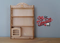 1:12 scale miniature unpainted wood bookshelf with scalloped top, three shelves and a small toy box, on a wood table