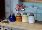 1:12 scale miniature kitchen canisters with cork lids in navy, brown, cream and white, set of 4, on a wood counter