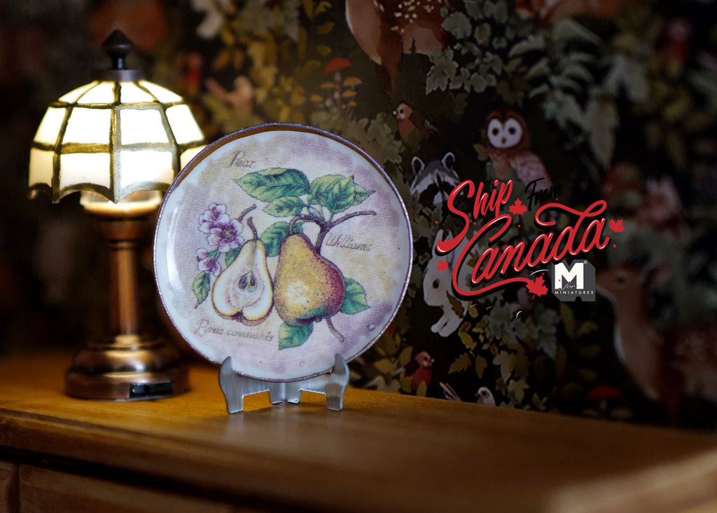 1:12 scale miniature ceramic decorative plate with pear design and stand, shown beside a lit table lamp