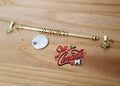 1:12 scale miniature expanding brass metal curtain rod with 2 hangers and 10 rings, on a wood surface beside a coin