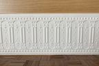 1:12 scale miniature ornate arched panel wainscot in white with embossed arches, shown along a wall above a wood floor