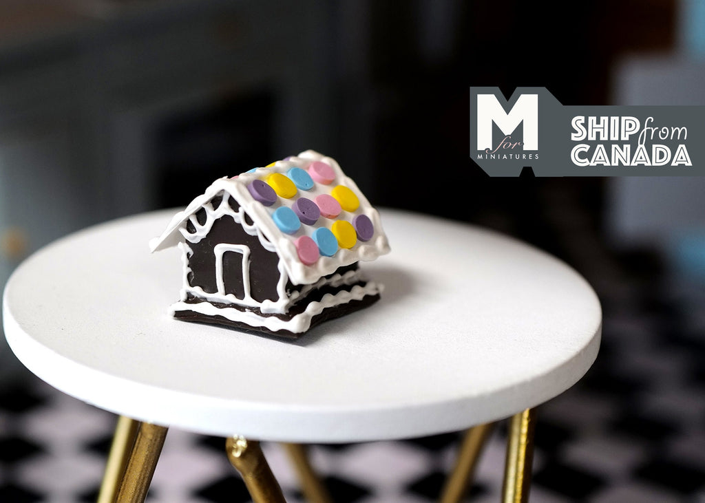 1:12 scale miniature Christmas gingerbread house with pastel macaron roof and white icing, shown on a white side table