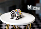 1:12 scale miniature Christmas gingerbread house with pastel macaron roof and white icing, shown on a white side table