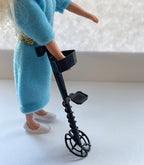 1:12 scale miniature metal detector in black with arm cuff, shown held by a doll in a blue dress