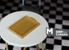 1:12 scale miniature wood serving tray in golden tone with a raised rim and cutout handles, shown on a white table