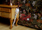 1:12 scale miniature lace parasol umbrella in white floral print with brown handle, shown leaning on a wood table