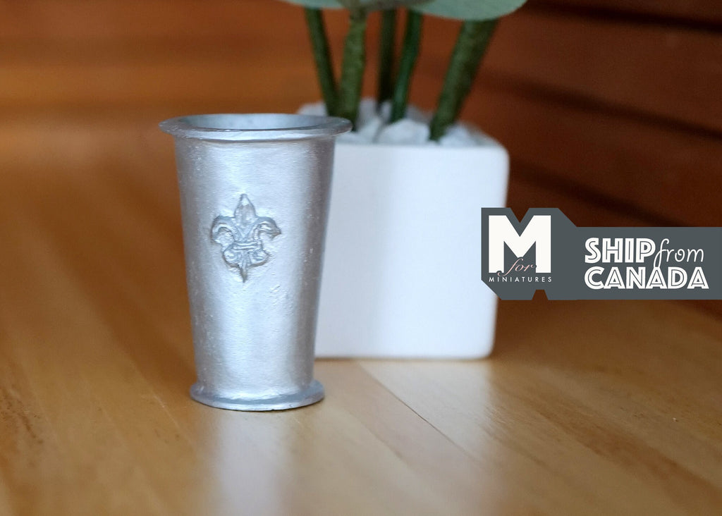 1:12 scale miniature large metal tree pot in silver, bucket style with a round emblem, shown on a wood floor
