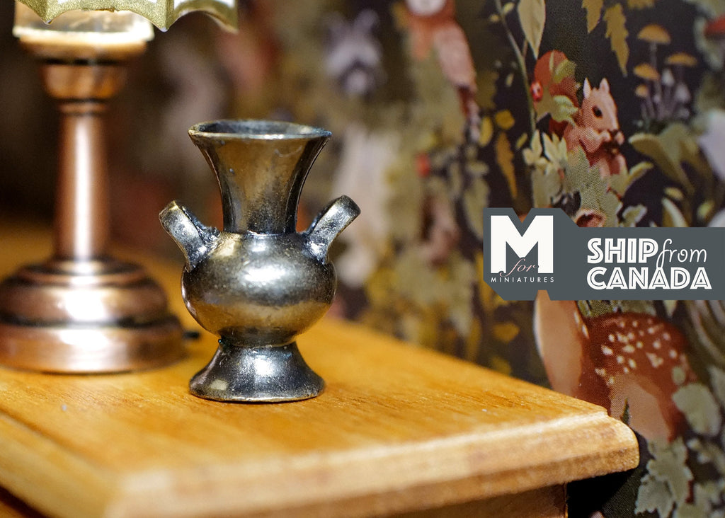 1:12 scale miniature brass metal ewer vase with handle and flared rim, shown on a wood table against floral wallpaper